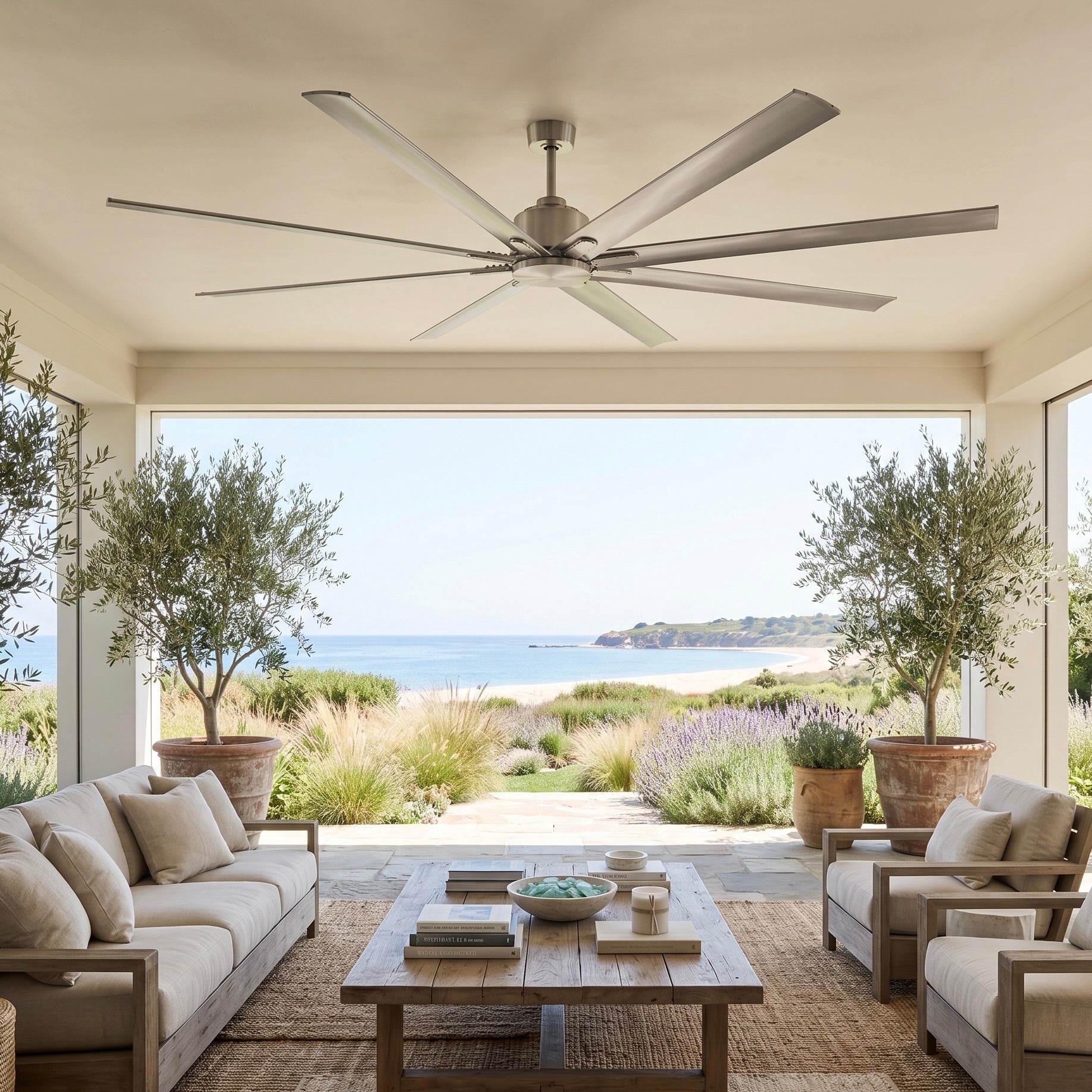 Extra-large outdoor ceiling fans — Orca H₂O® 100-inch wet-rated in brushed nickel on a covered porch overlooking the coast